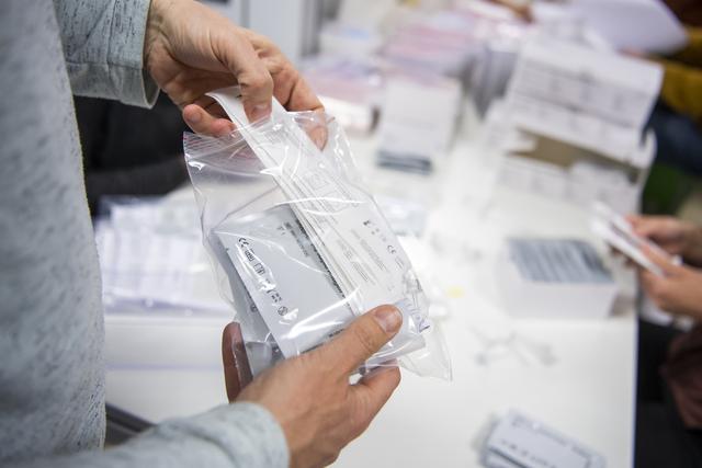 Un sachet contenant des autotests pour le dépistage du coronavirus. [Keystone - Jean-Christophe Bott]