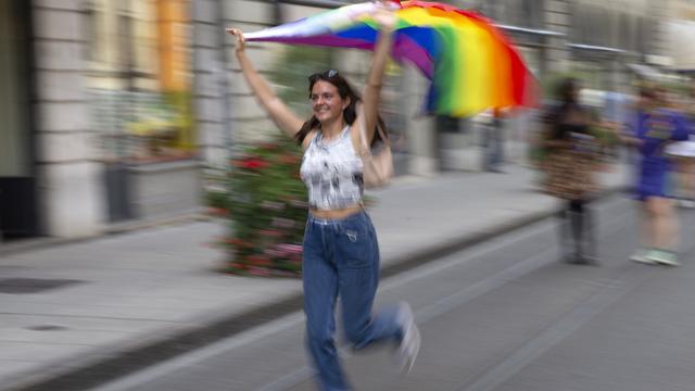 Une personne arbore le drapeau LGBT+ dans une rue de Genève, à l'occasion de la Marche des fiertés, le 11 septembre 2021. [Keystone - Salvatore Di Nolfi]