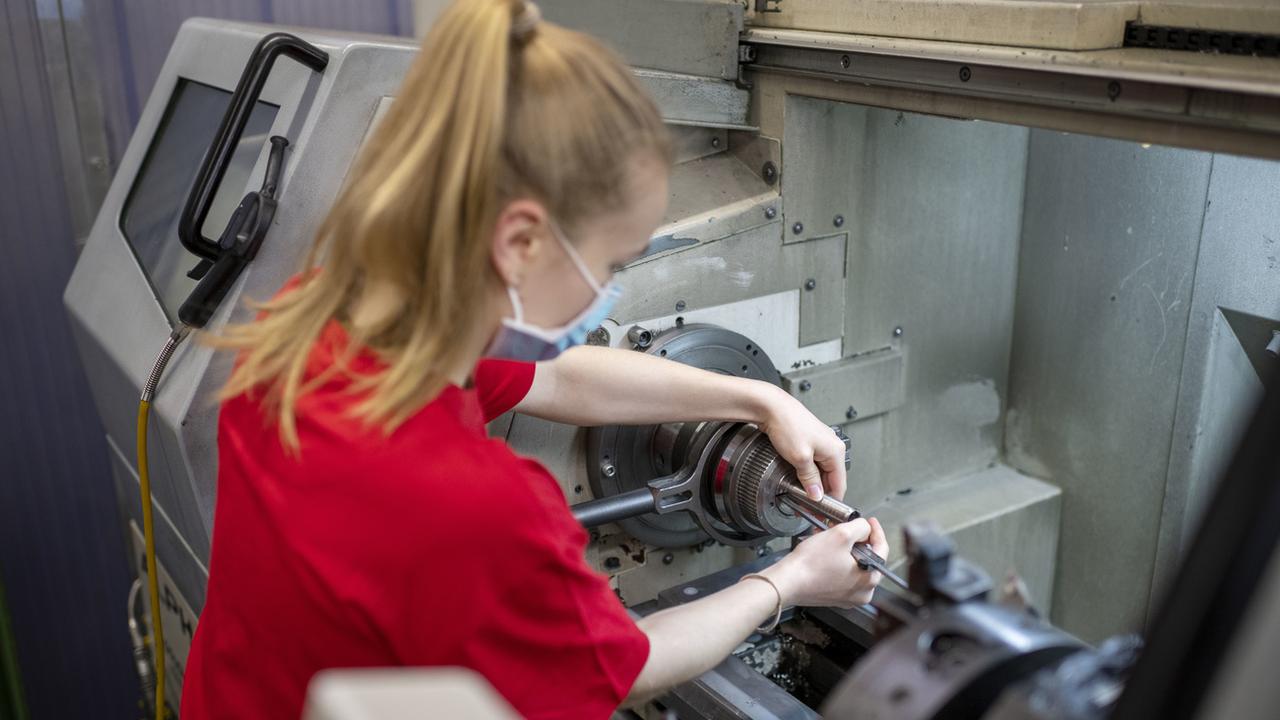 Une apprentie monte une pièce dans une machine, le 15 avril 2021 dans l'atelier de mécanique de la LBB à Bâle. [Keystone - Christian Beutler]