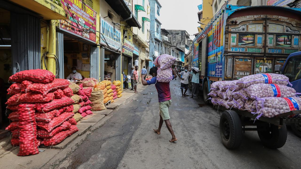 Des travailleurs déchargent des produits alimentaires essentiels sur un marché de gros à Colombo, au Sri Lanka. [Keystone - EPA/Chamila Karunarathne]