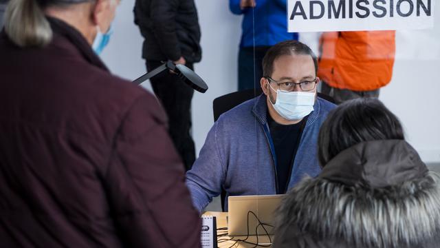 Une patiente discute dans l'espace des admissions d'un centre vaccinal en Valais (image d'illustration). [Keystone - Jean-Christophe Bott]