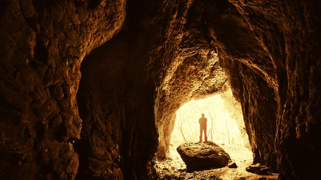 Homme debout devant une entrée de grotte. [depositphotos - photocosma]