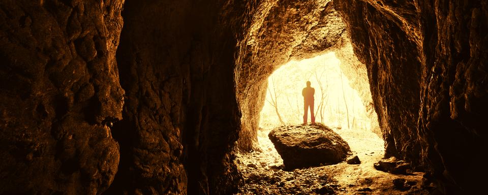 Homme debout devant une entrée de grotte. [depositphotos - photocosma]