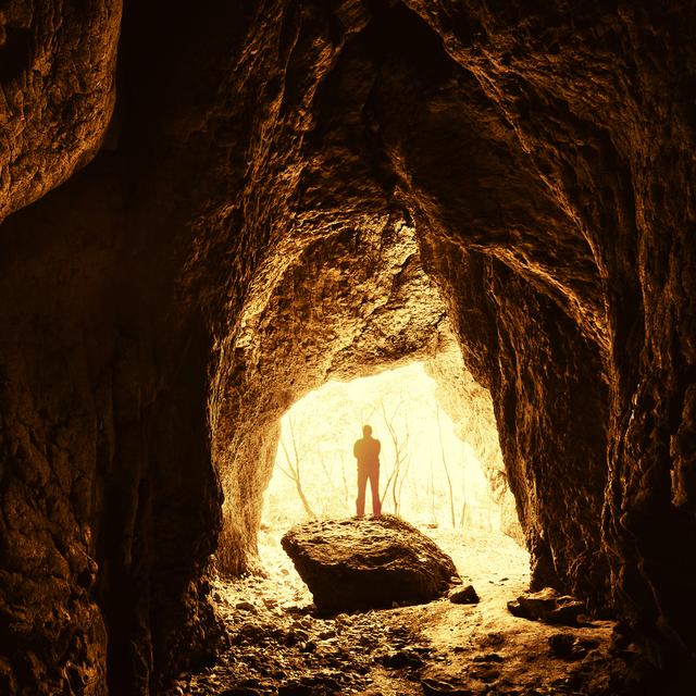 Homme debout devant une entrée de grotte. [depositphotos - photocosma]