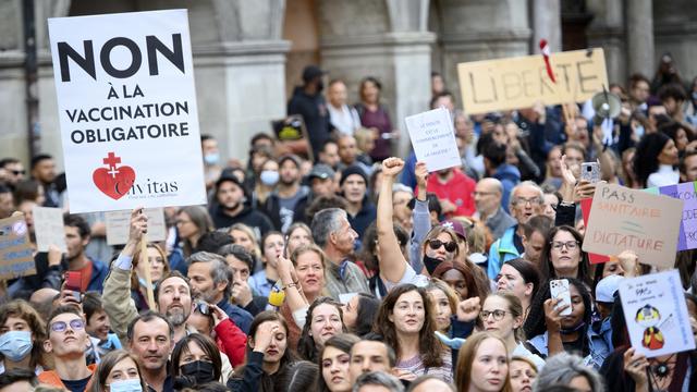 Des personnes brandissent des pancartes contre le certificat Covid lors d'une manifestation à Lausanne, le 21 septembre 2021. [KEYSTONE - Laurent Gillieron]