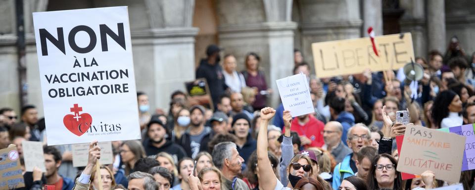 Des personnes brandissent des pancartes contre le certificat Covid lors d'une manifestation à Lausanne, le 21 septembre 2021. [KEYSTONE - Laurent Gillieron]