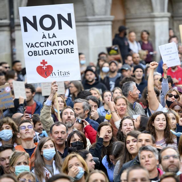 Des personnes brandissent des pancartes contre le certificat Covid lors d'une manifestation à Lausanne, le 21 septembre 2021. [KEYSTONE - Laurent Gillieron]