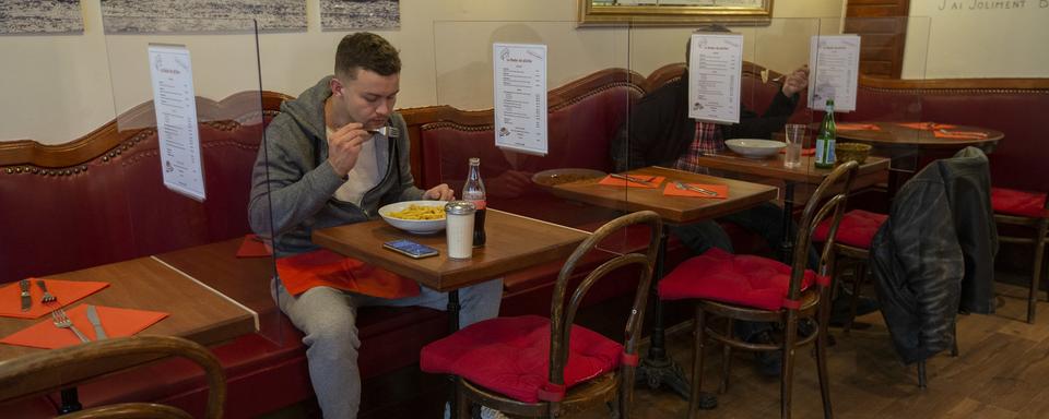 Des clients mangent sur des tables séparées par du plexiglas comme mesure préventive contre la propagation du coronavirus à Genève, le 13 mai 2020. [Keystone - Salvatore Di Nolfi]