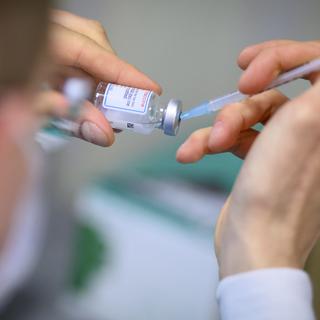 Un préparateur remplit une seringue de vaccin. [Keystone - Laurent Gillieron]