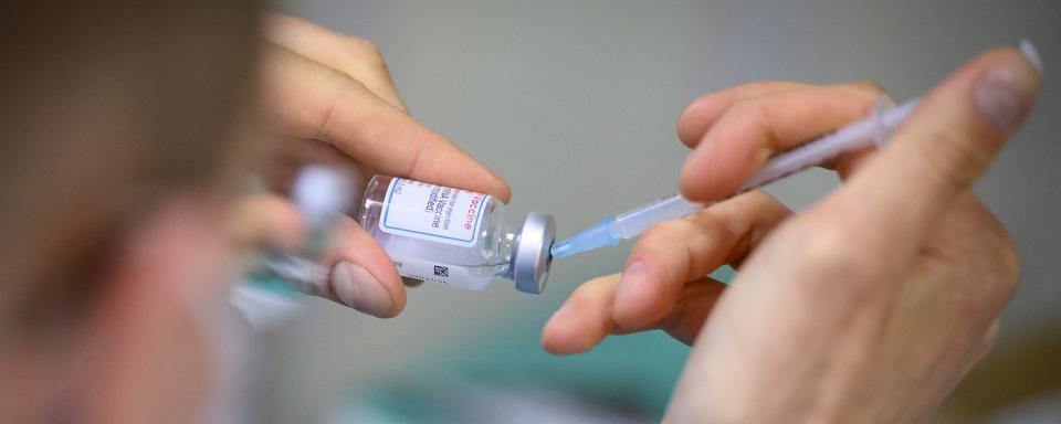 Un préparateur remplit une seringue de vaccin. [Keystone - Laurent Gillieron]