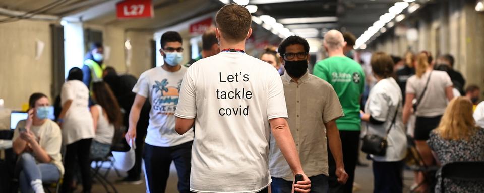 "Attaquons-nous au Covid", dit le t-shirt de cette personne, dans le vaccinodrome du Twickenham rugby stadium, à Londres, le 31 mai 2021. [Keystone/epa - Andy Rain]