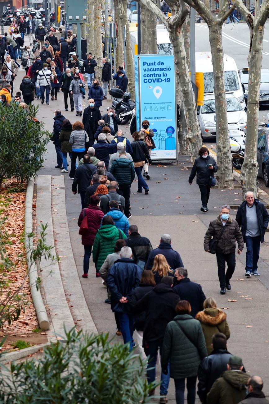 Des personnes attendent pour recevoir une dose de vaccin contre le Covid dans un centre de Barcelone, le 23 décembre 2021. [Keystone/EPA - Alejandro Garcia]