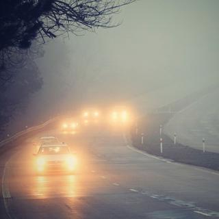 Des voitures circulent sur une route plongée dans le brouillard. [Depositphotos - montypeter]