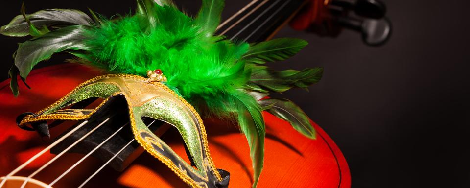 Masque vénitien avec plumes vertes sur violoncelle [Depositphotos - serrnovik]