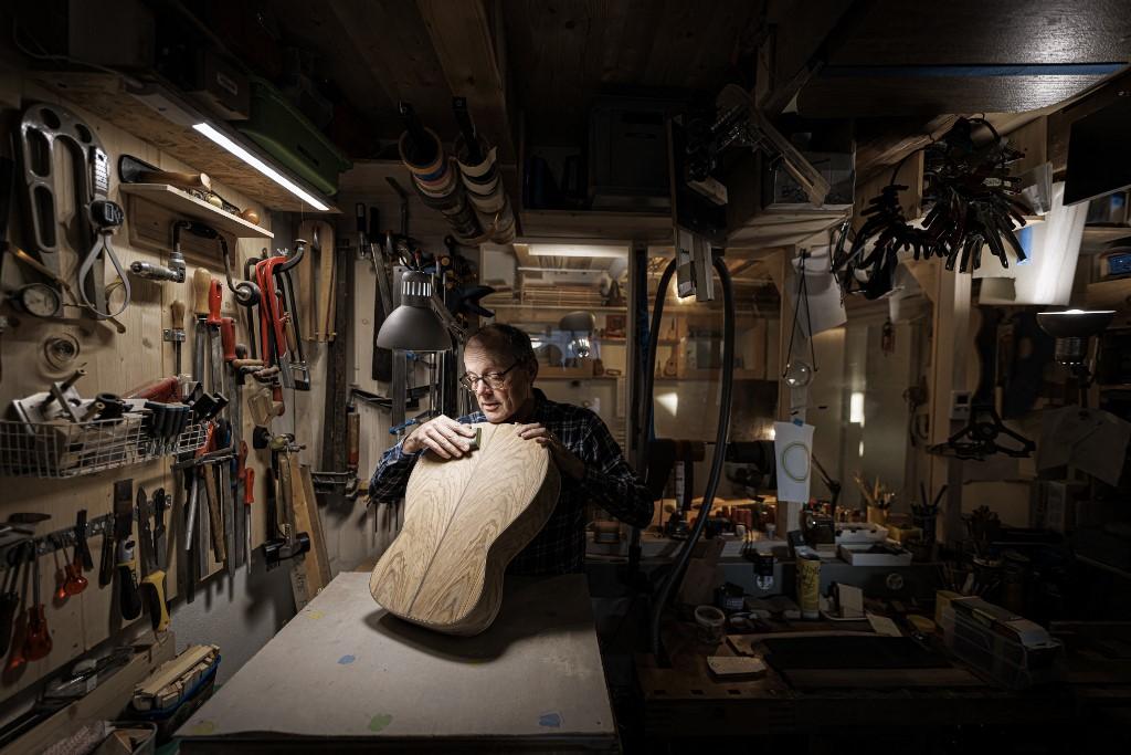 Le luthier Philippe Ramel ponce la table d'harmonie d'une guitare, réalisée principalement en bois de la forêt du Risoux. Chardonne, le 16 novembre 2022. [AFP - Valentin Flauraud]