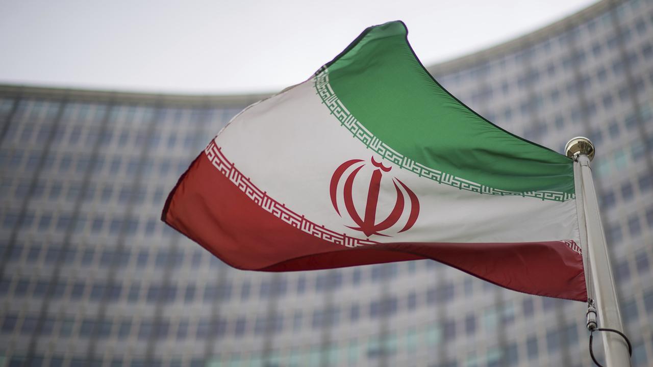 Le drapeau iranien devant le bâtiment de l'Agence internationale de l'énergie atomique. [Keystone - Michael Gruber]