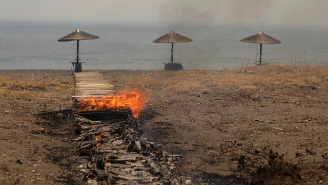 Un bar de plage en feu sur l'île de Lesbos. [Reuters - Elias Marcou]