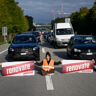 Des militants écologistes membres de Renovate Switzerland se sont assis sur la route lors d'une action de blocage de l'autoroute A1 à l'entrée de Lausanne, mardi 4 octobre 2022. [KEYSTONE - Laurent Gillieron]