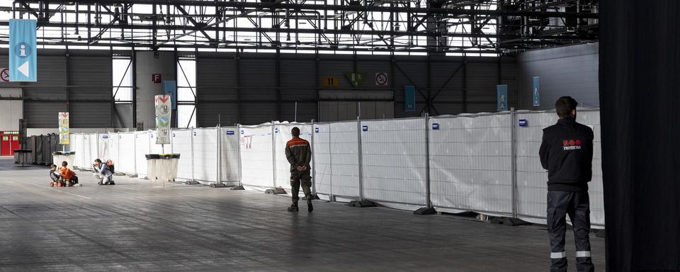 Des enfants réfugiés ukrainiens jouent devant les caisses de l'abri d'urgence pour réfugiés ukrainiens dans la halle 1 de Palexpo, mardi 12 avril 2022 à Genève. [KEYSTONE - Salvatore Di Nolfi]