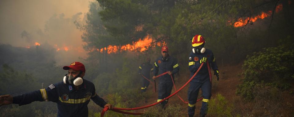 Des pompiers luttent pour éteindre un feu de forêt près de la station balnéaire de Vatera, sur l'île de Lesvos, dans la mer Égée orientale, en Grèce, samedi 23 juillet 2022. [AP Photo/KEYSTONE - Panagiotis Balaskas]