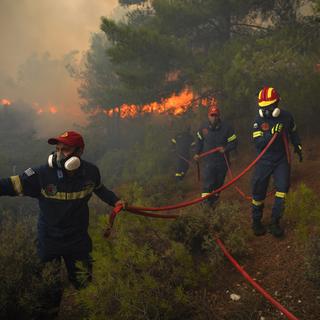 Des pompiers luttent pour éteindre un feu de forêt près de la station balnéaire de Vatera, sur l'île de Lesvos, dans la mer Égée orientale, en Grèce, samedi 23 juillet 2022. [AP Photo/KEYSTONE - Panagiotis Balaskas]