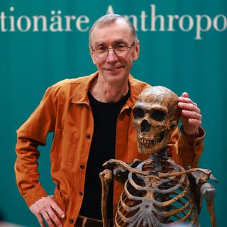 3 octobre 2022: le prix Nobel de médecine pour ses recherches sur les humains archaïques, le Suédois Svante Paabo pose avec une squelette d'homme de Néanderthal. [EPA/Keystone - Hannibal Hanschke]