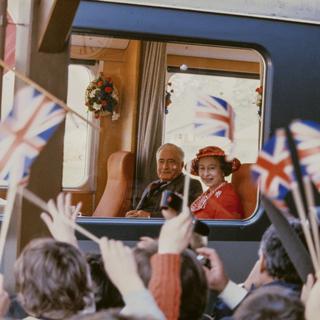 La foule se presse à Wimmis, sur la ligne du Montreux-Oberland Bernois, pour saluer la reine Elizabeth II d'Angleterre et le président de la Confédération Georges-André Chevallaz le 30 avril 1980 lors de la visite officielle de la reine en Suisse. [Keystone]