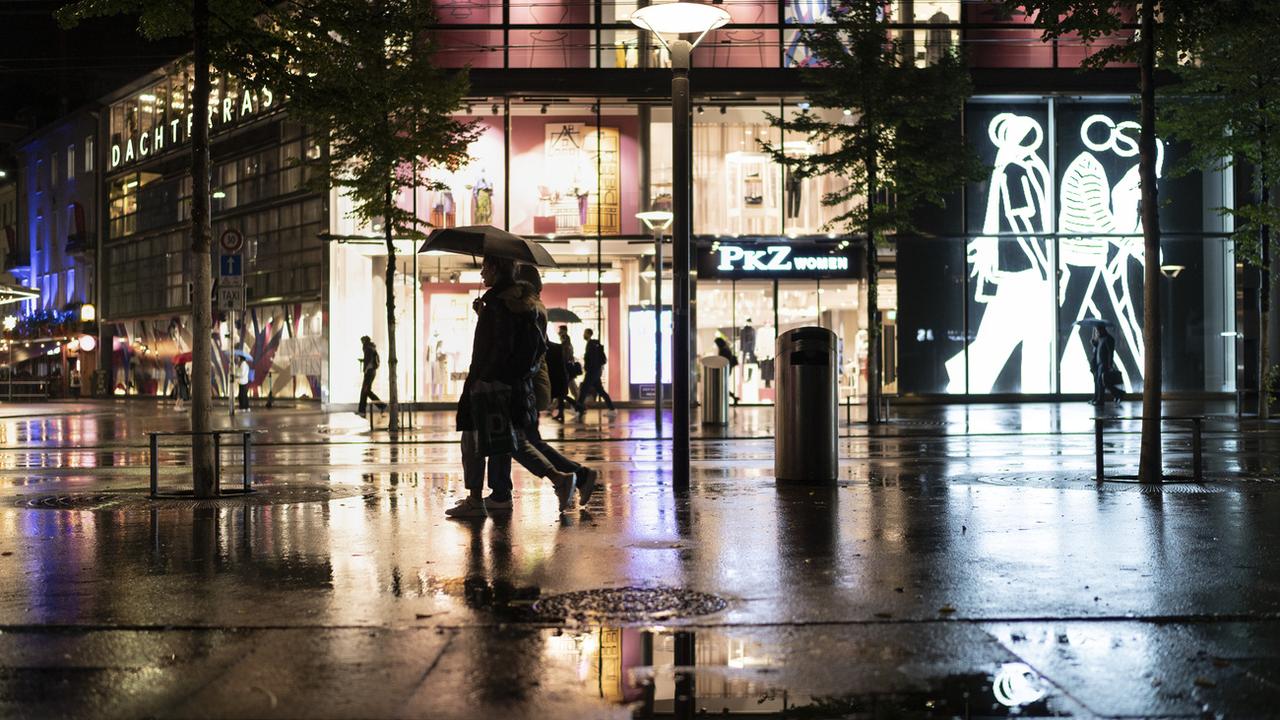 Des passants bravent la pluie en cette soirée du 27 septembre 2022, dans les rues de Zurich. [KEYSTONE - Gaetan Bally]