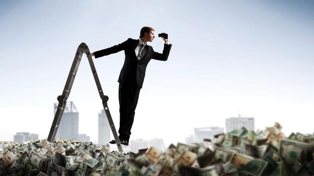 Un homme en costume sur une échelle regarde l'horizon au dessus d'une mer de billets. [Depositphotos - SergeyNivens]