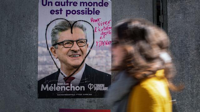 Une femme passe devant une affiche du candidat de gauche, Jean-Luc Mélenchon, le 9 avril 2022 à Paris. [AFP - Joël Saget]