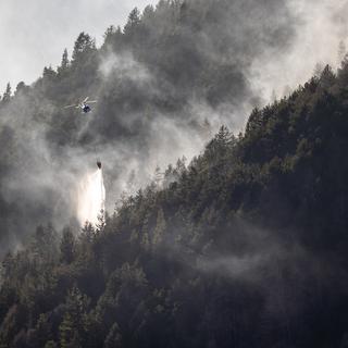 Un hélicoptère déverse de l'eau pour tenter d'éteindre l'incendie au Monte Gambarogno, le 1er février 2022. [(KEYSTONE - Ti-Press/Massimo Piccoli]