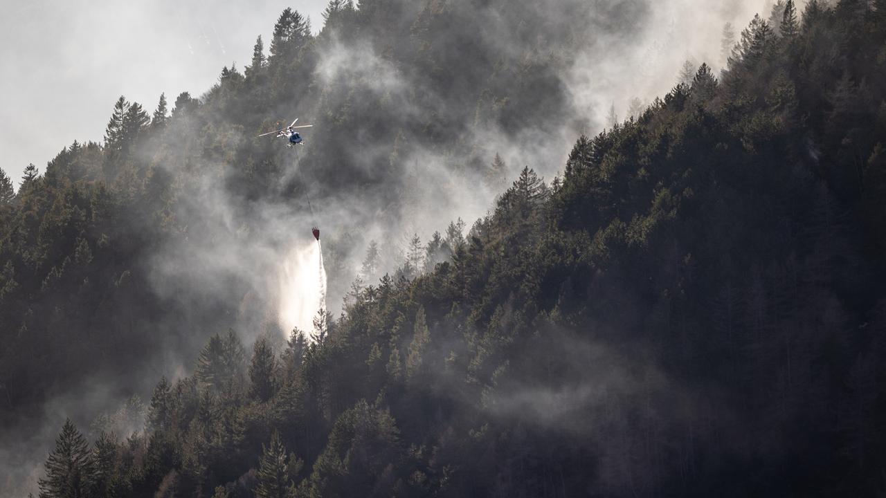 Un hélicoptère déverse de l'eau pour tenter d'éteindre l'incendie au Monte Gambarogno, le 1er février 2022. [(KEYSTONE - Ti-Press/Massimo Piccoli]