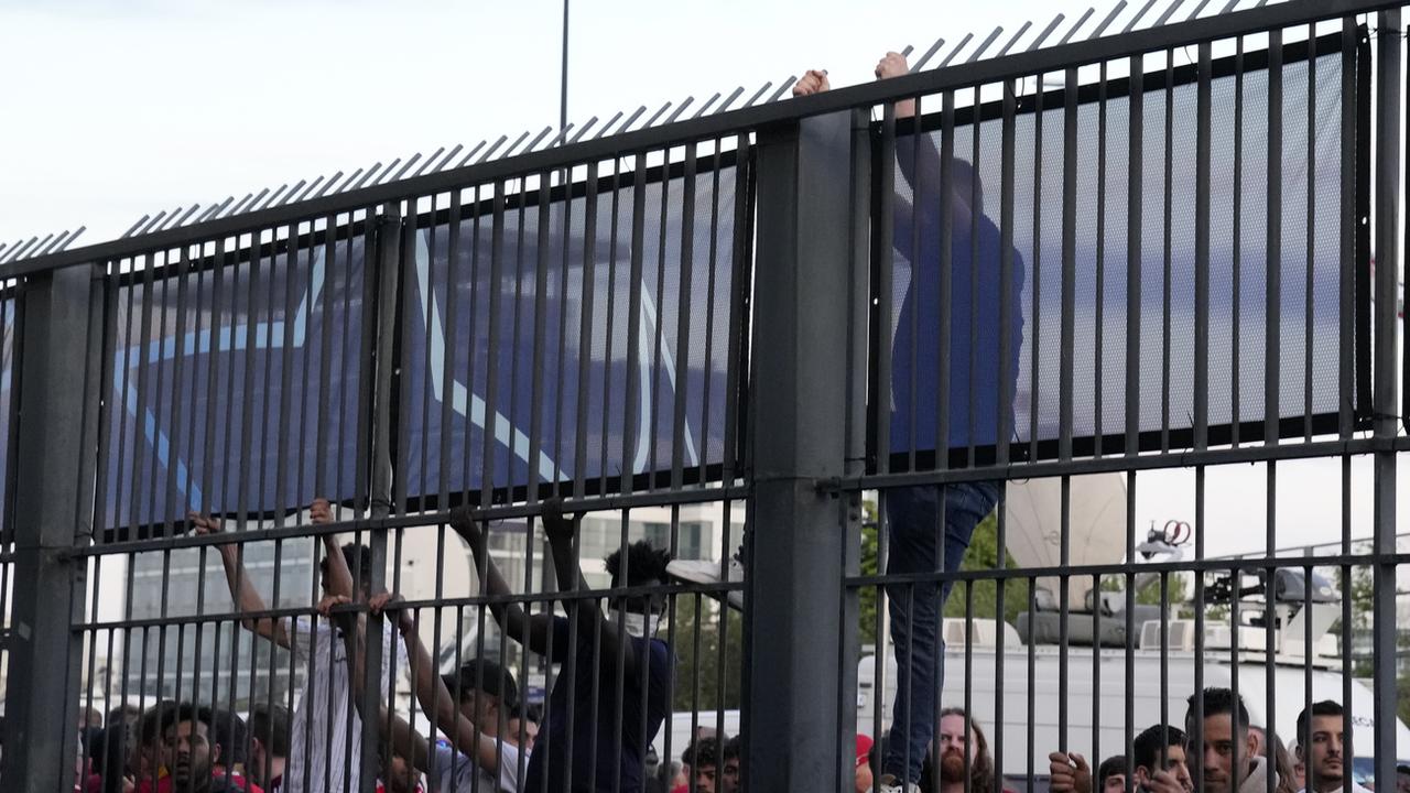 Des supporters ont tenté d'escalader les barrières pour entrer dans le stade. [Keystone/AP - Christophe Ena]