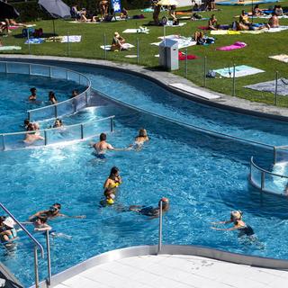 Des personnes profitent du soleil à la piscine de Renens (VD). (image d'illustration) [Keystone - Jean-Christophe Bott]