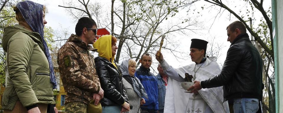 Le prêtre orthodoxe Alexander Ivlev bénit les croyants lors de la célébration de Pâques devant l'église Saint-Pantaléon à Kramatorsk, en Ukraine, dimanche 24 avril 2022. [AP Photo/Keystone - Andriy Adriyenko]