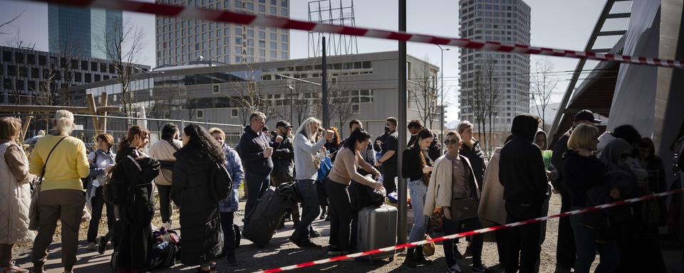 Des réfugiés ukrainiens font la queue et attendent d'être enregistrés devant le centre fédéral d'asile de Zurich, le dimanche 13 mars 2022 à Zurich. [KEYSTONE - Michael Buholzer]