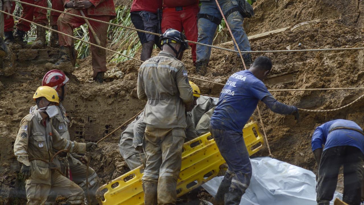 Les pompiers recherchent les corps des victimes dans la boue après les glissements de terrain. [Genival Paparazzi]