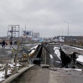 Des personnes marchent sur un pont détruit à Bucha, près de Kiev. [Reuters]
