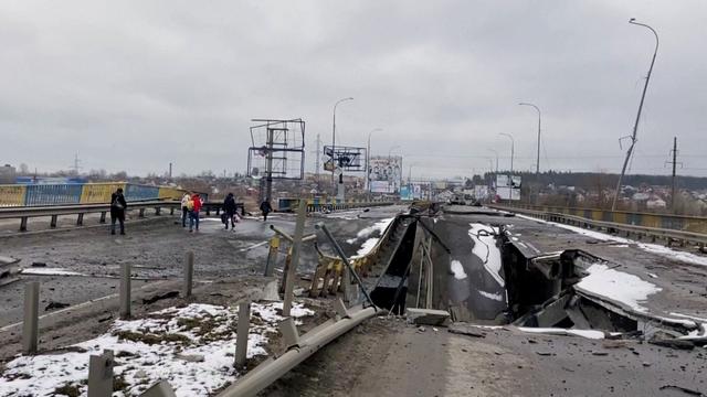 Des personnes marchent sur un pont détruit à Bucha, près de Kiev. [Reuters]