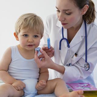 Une pédiatre donne un traitement homéopathique à un jeune enfant. [Depositphotos - imagepointfr]