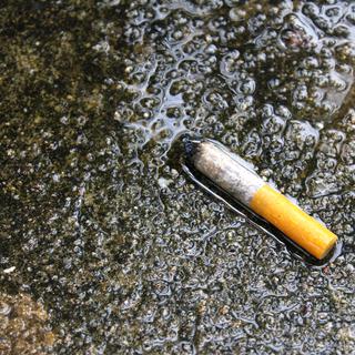 Une mégot de cigarette sur le bord d'un lac. [Depositphotos - bannerwega]
