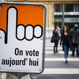 Des personnes marchent à côté d'un bureau de vote à Neuchâtel. Le canton a refusé le droit de vote à 16 ans en février 2020. [Keystone - Jean-Christophe Bott]