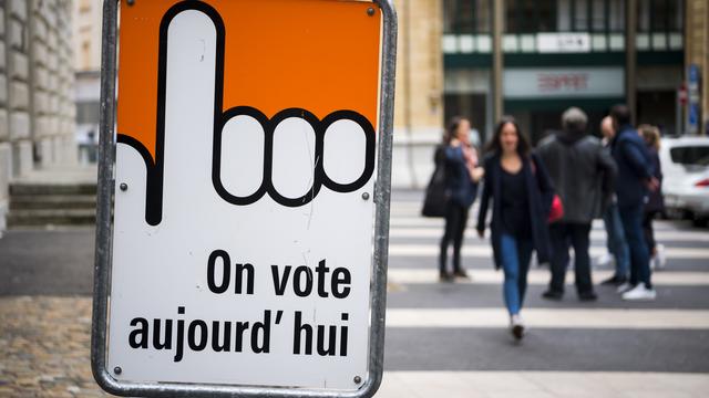 Des personnes marchent à côté d'un bureau de vote à Neuchâtel. Le canton a refusé le droit de vote à 16 ans en février 2020. [Keystone - Jean-Christophe Bott]