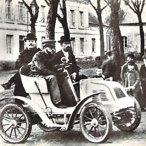 Henry Bauchet en 1900 au volant de sa "Sirène", qu'il a créée un an plus tôt. Moteur de 5 CV à l'avant, deux cylindres en V, refroidissement par air, transmission sans chaîne, boîte de vitesses à pignons baladeurs et prise directe, allumage électrique connu plus tard sous le nom de "Delco".