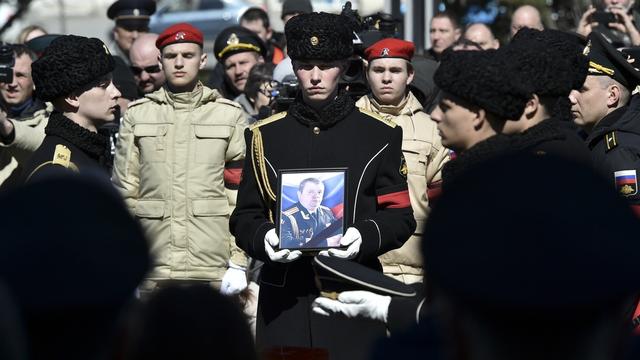 Un militaire porte la photo du Capitaine Andrei Paliy, commandant adjoint de la flotte russe de la mer Noire, lors d'une cérémonie d'adieu à Sébastopol, en Crimée, mercredi 23 mars 2022. [AP Photo/KEYSTONE]