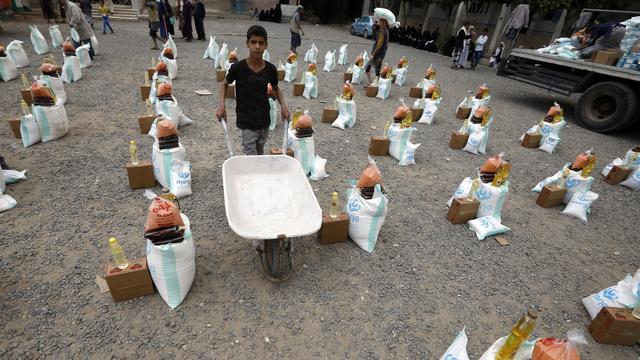 Un Yéménite pousse une brouette vide à travers des rations alimentaires d'urgence, fournies par l'agence de secours Mona, pour les personnes touchées par la guerre, à Sana'a, au Yémen, le 24 avril 2022. [EPA/KEYSTONE - Yahya Arhab]