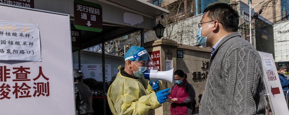 Un travailleur médical dirige les personnes entrant dans un hôpital, à Shanghai, en Chine, le 15 mars 2022. [Keystone - ALEX PLAVEVSKI]