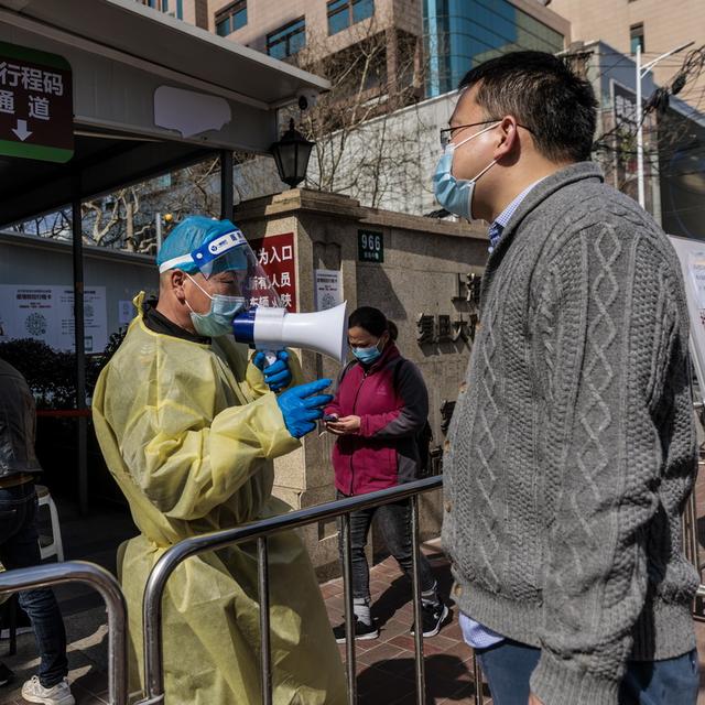 Un travailleur médical dirige les personnes entrant dans un hôpital, à Shanghai, en Chine, le 15 mars 2022. [Keystone - ALEX PLAVEVSKI]