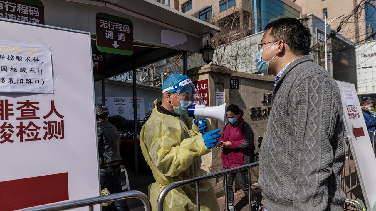 Un travailleur médical dirige les personnes entrant dans un hôpital, à Shanghai, en Chine, le 15 mars 2022. [Keystone - ALEX PLAVEVSKI]