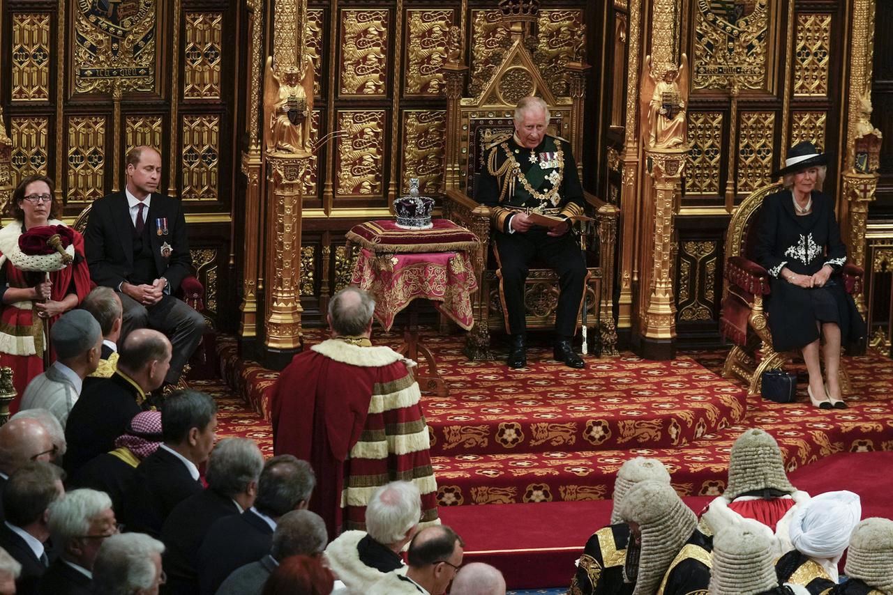 Charles prend la place d'Elizabeth II pour le traditionnel discours devant le Parlement, avec William à sa droite et Camilla à sa gauche. [Keystone - AP Photo/Alastair Grant, Pool]